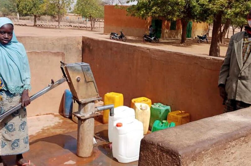 Retired civil servant Lambda and two of his granddaughters at a water pump in the commune of Tougouri, northern Burkina Faso.