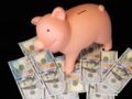 Piggy bank standing over $100 bills