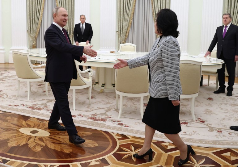 Vladimir Putin holds out his hand as he walks towards North Korea's Foreign Minister Choe Son Hui in the Kremlin. He is smiling and looks relaxed. She is also extending her hand.